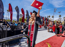 Graduate raising their diploma in celebration.